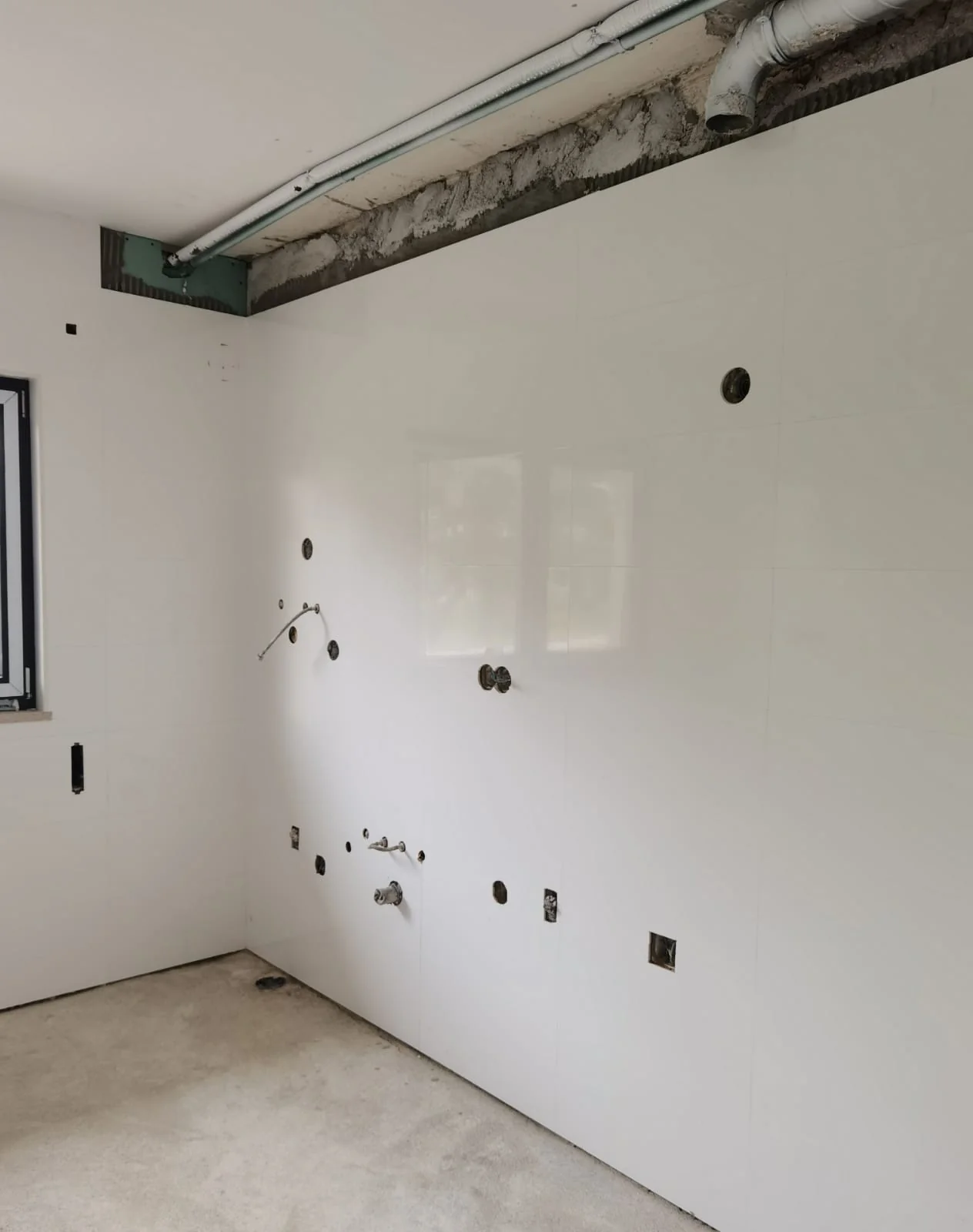 Parede de cozinha revestida com cerâmica branca de grande formato em execução