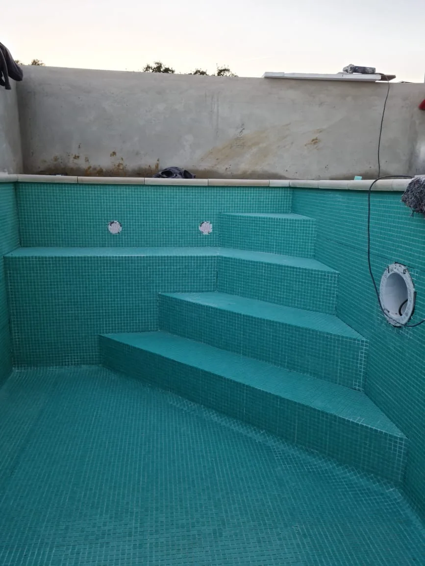 Piscina revestida com mosaico verde-água, banco integrado e escadas