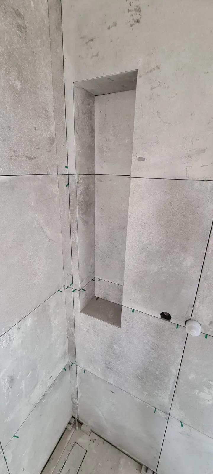 Nicho vertical revestido em cerâmica com cortes alinhados às juntas da parede