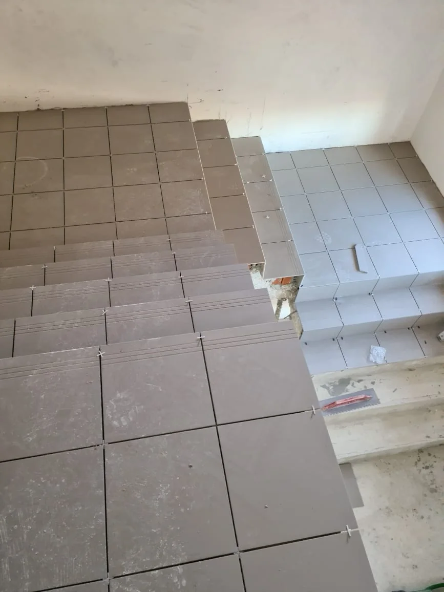 Escadas e patamar revestidos com peças cerâmicas cinzentas e juntas regulares
